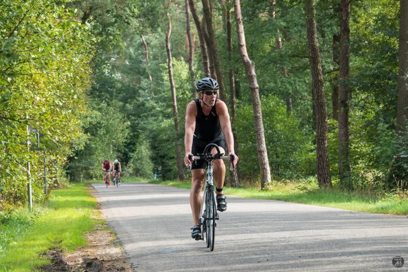Een man fietst over een weg in het bos.