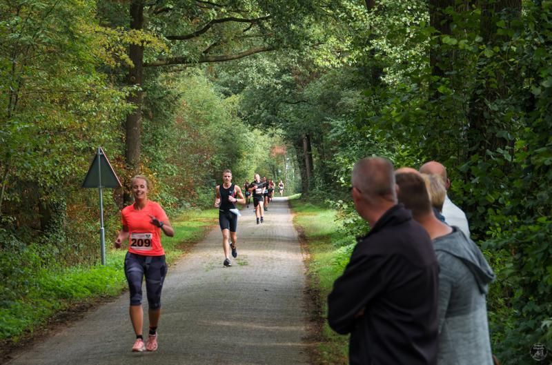 Een groep mensen rent over een weg in het bos.