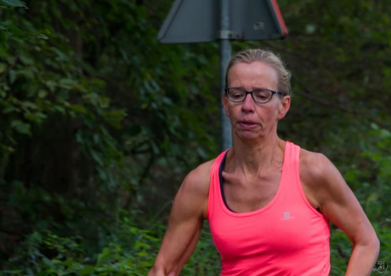 Een vrouw in een roze tanktop en een bril rent.