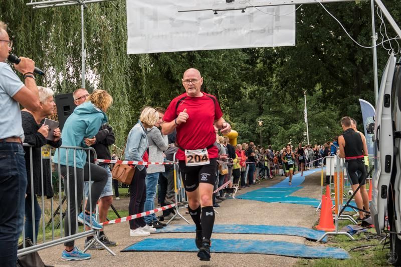 Een man rent een marathon voor een grote groep mensen.