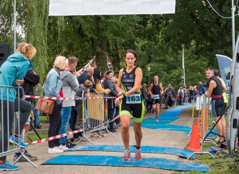 Een vrouw rent mee in een triatlon met het nummer 163 op haar shirt.