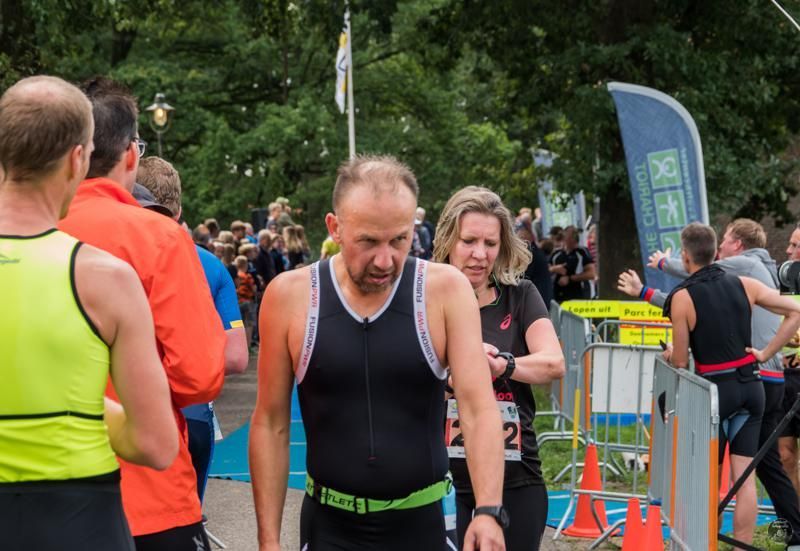 Een man in een triatlonpak staat voor een menigte mensen.