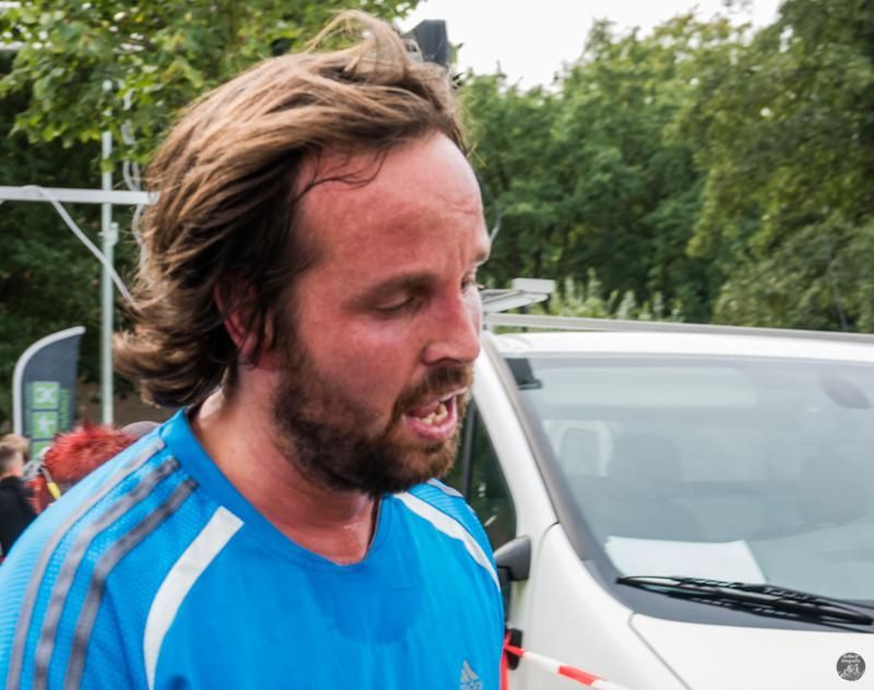 Een man met een baard draagt ​​een blauw adidas-shirt
