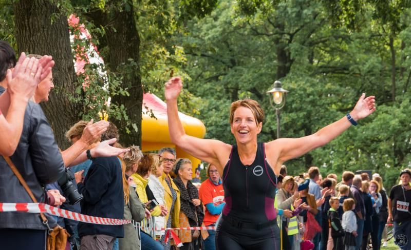 Een vrouw rent een marathon voor een grote groep mensen.