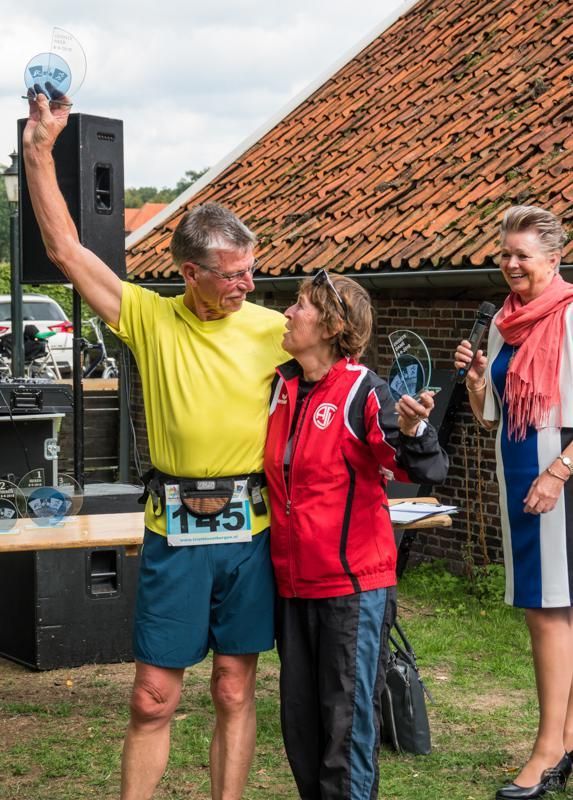 Een man houdt een trofee in zijn hand terwijl hij naast een vrouw staat.