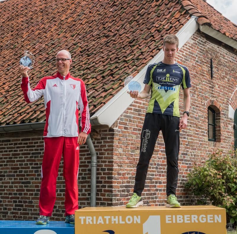 Twee mannen staan ​​op een podium met de tekst triathlon eibergen