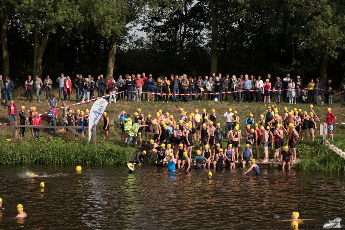 Een grote groep mensen staat rond een watermassa.