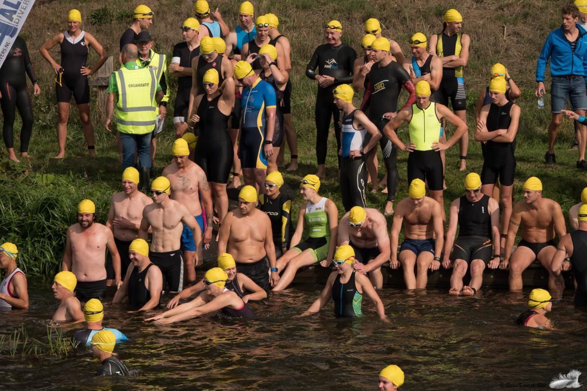 Een groep mensen met gele badmutsen staat in het water.