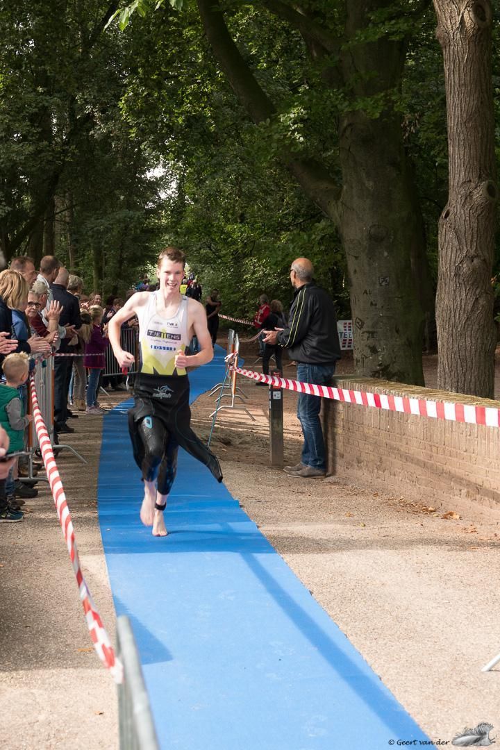 Een man rent over een blauwe loper voor een menigte.