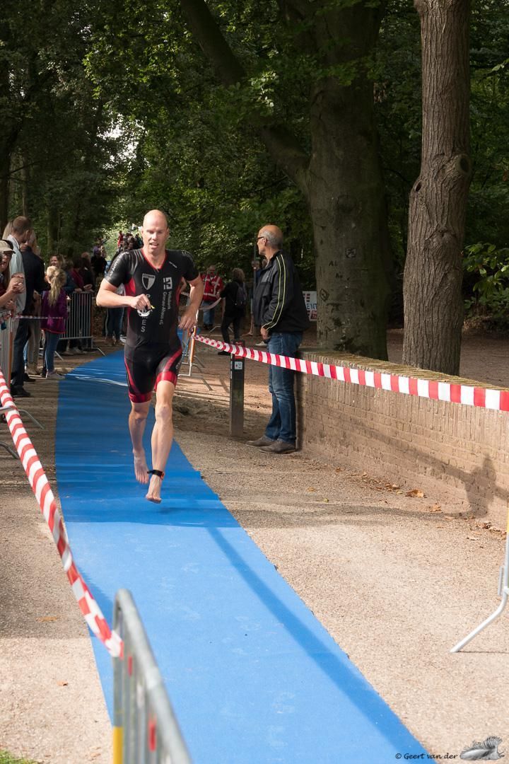 Een man rent op een blauwe loper in een park.