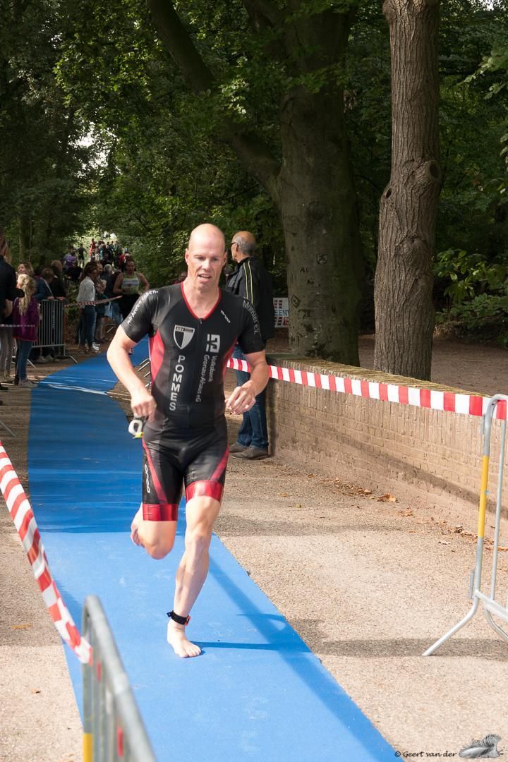 Een man in een wetsuit rent op een blauwe mat