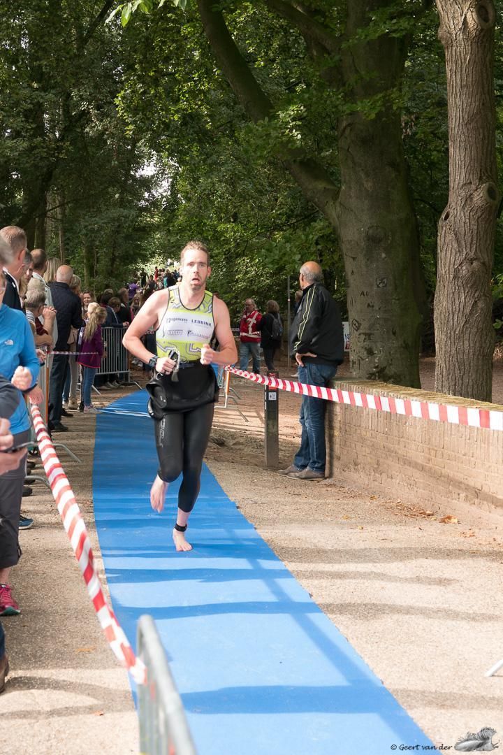 Een vrouw rent op een blauwe mat in een park.