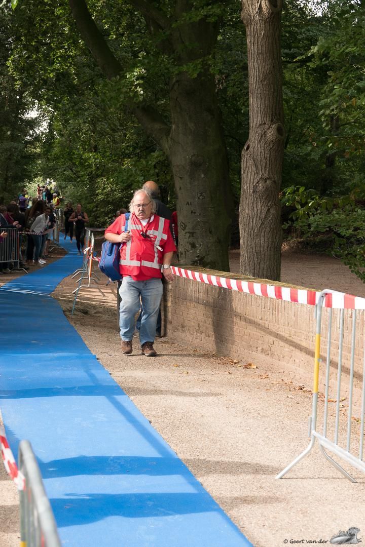 Een man in een rood shirt loopt over een blauw pad.