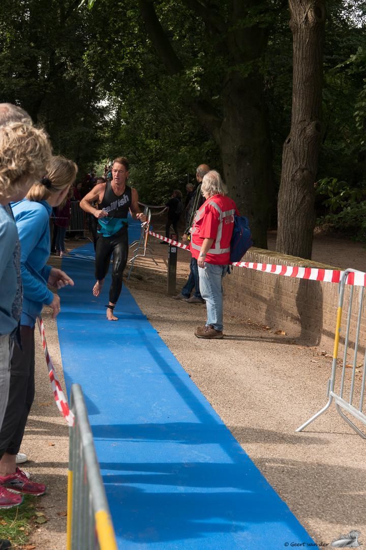 Een vrouw rent op een blauwe loper in een park.