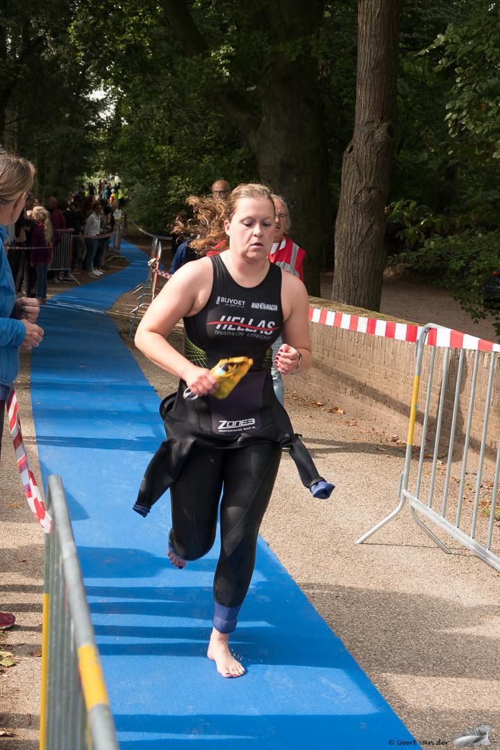 Een vrouw in een wetsuit rent op een blauwe loper.