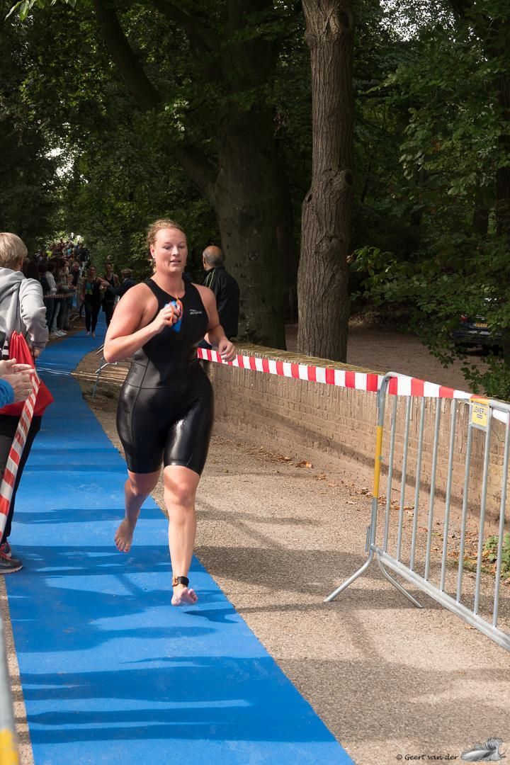 Een vrouw in een wetsuit rent op een blauwe mat.