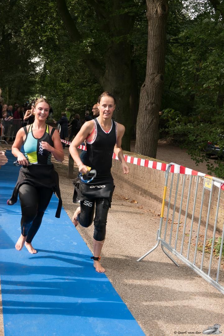 Twee vrouwen rennen op blote voeten op een blauwe mat.