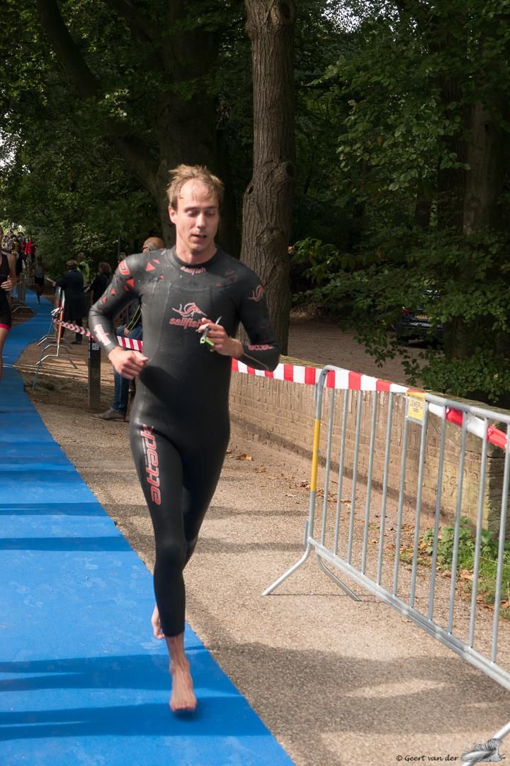 Een man in een wetsuit rent op een blauwe mat.