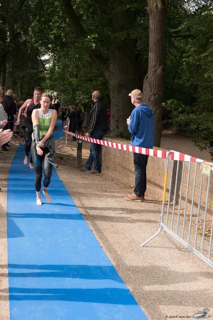 Een vrouw passeert de finish van een race op een blauwe loper.