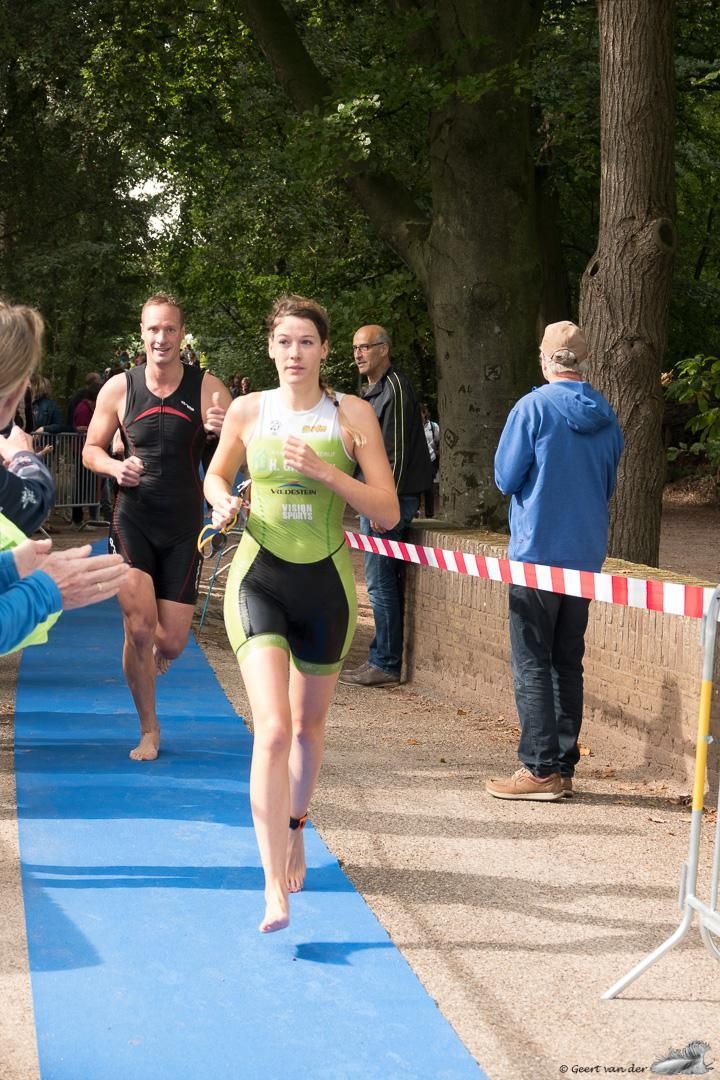 Een vrouw rent op een blauwe loper in een park.
