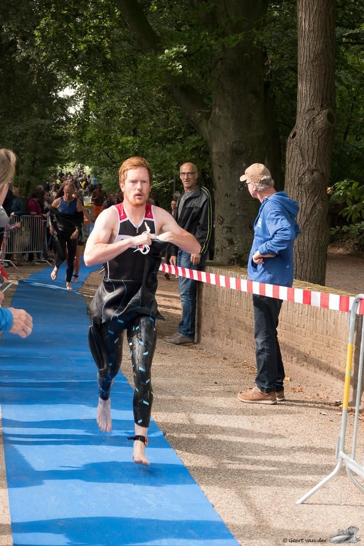 Een man in een wetsuit rent over een blauwe loper.