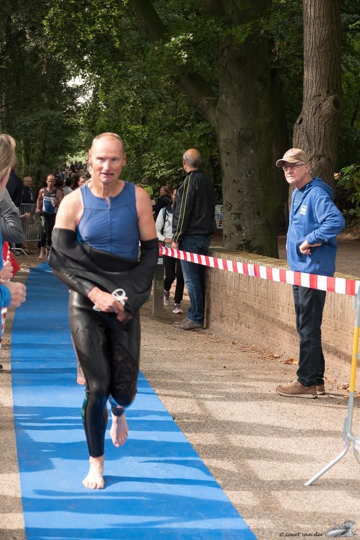 Een man in een wetsuit rent over een blauwe loper.