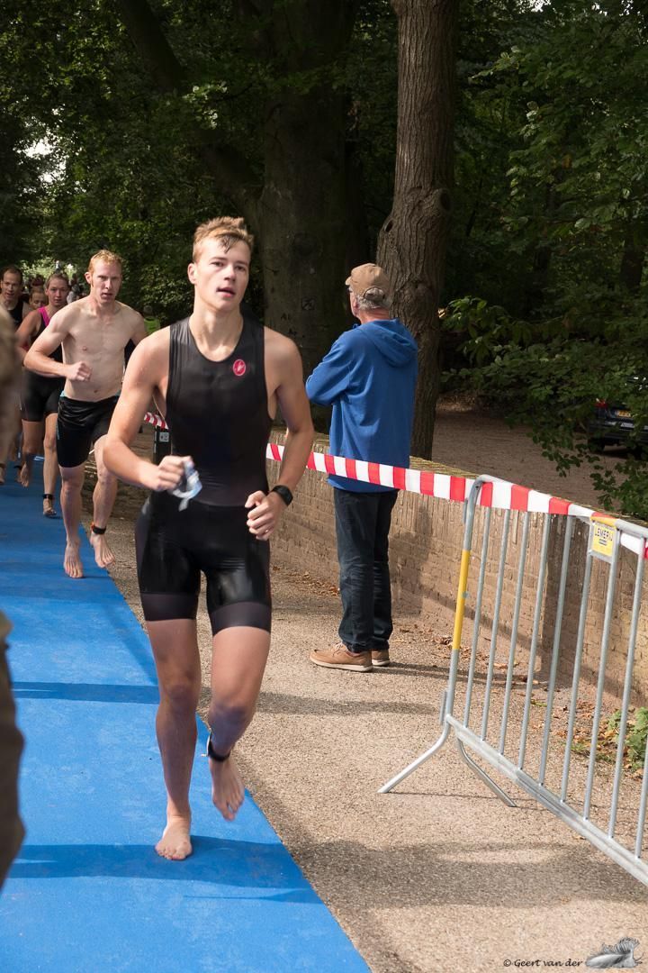 Een man rent op een blauwe loper tijdens een triatlon.