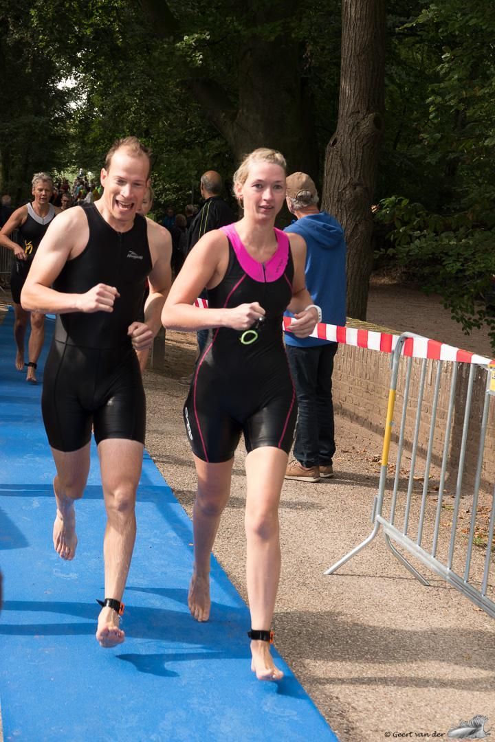 Een man en een vrouw rennen op een blauwe baan