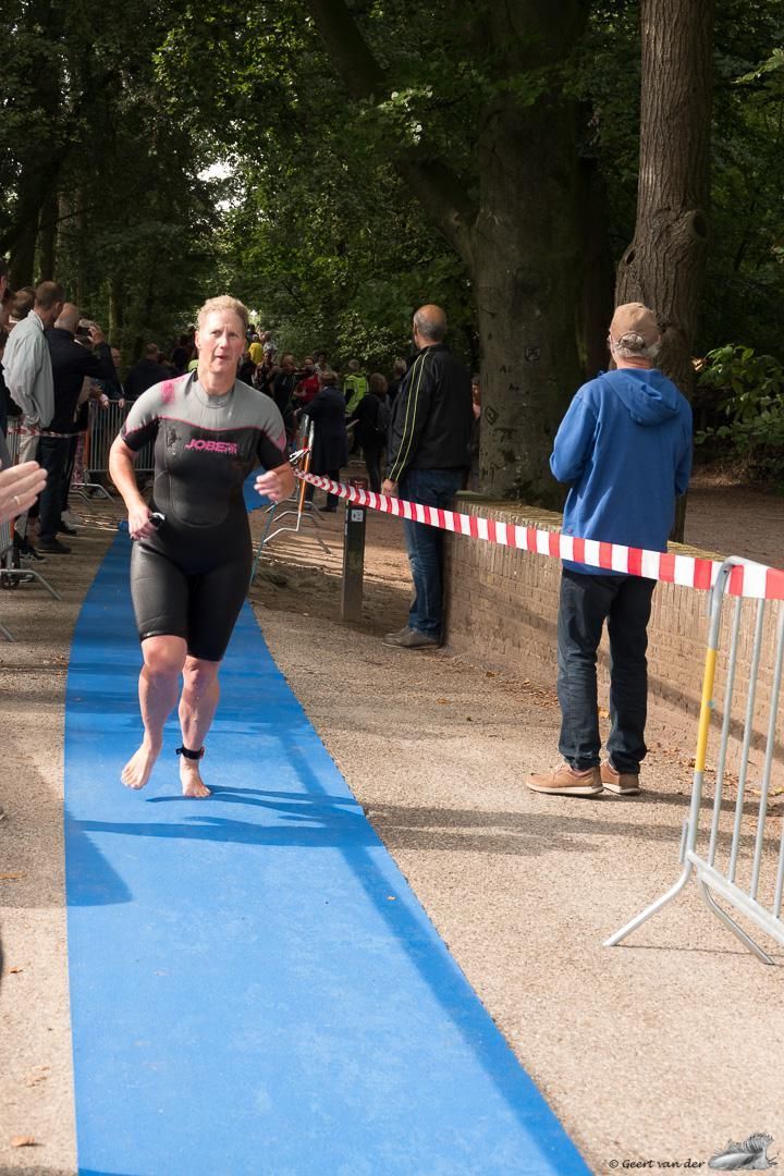 Een vrouw in een wetsuit rent op een blauwe loper.