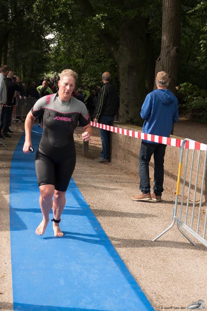 Een vrouw in een wetsuit rent op een blauwe mat.