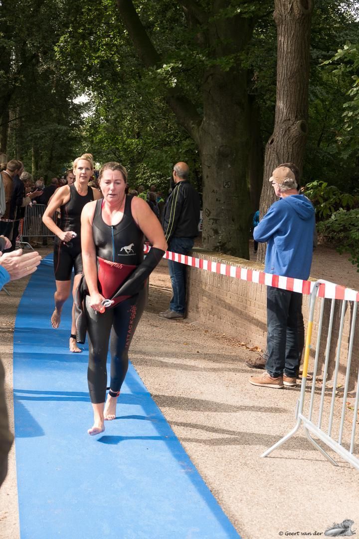 Een vrouw in een wetsuit loopt over een blauwe loper.