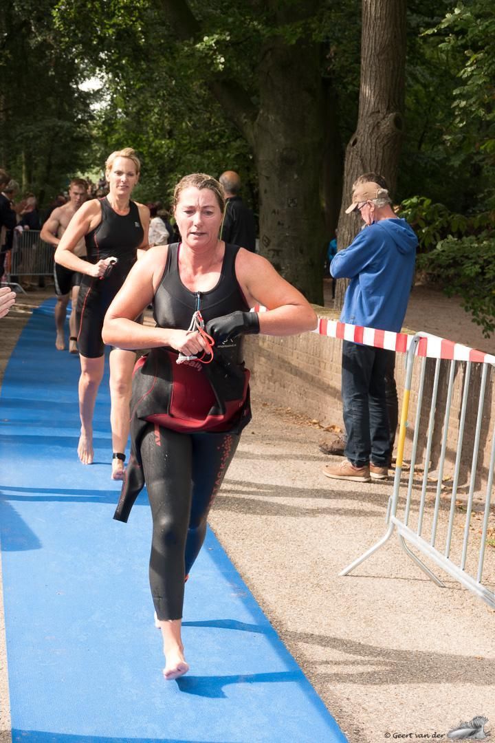 Een vrouw in een wetsuit rent op een blauwe loper.