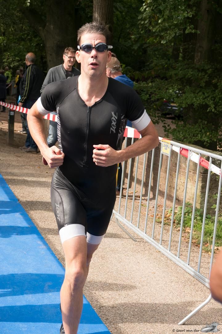 Een man met een zonnebril rent over een blauwe loper.