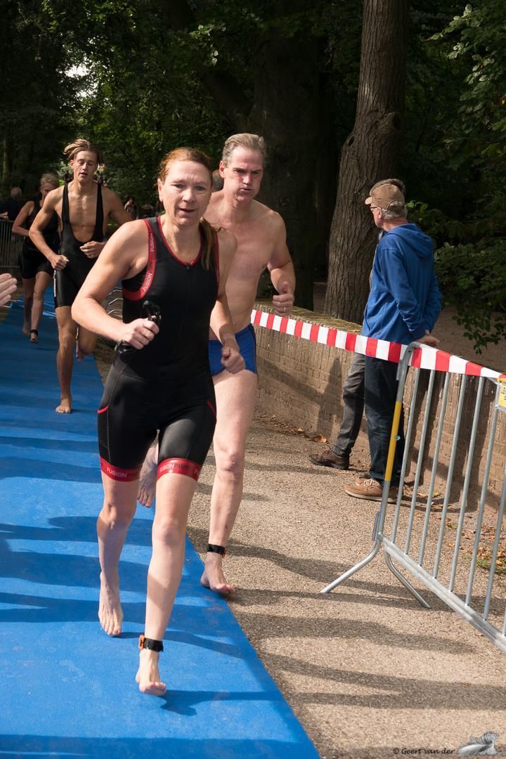 Een groep mensen rent op een blauwe baan.