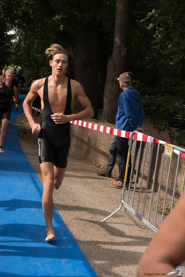 Een man zonder shirt rent op een blauwe baan.