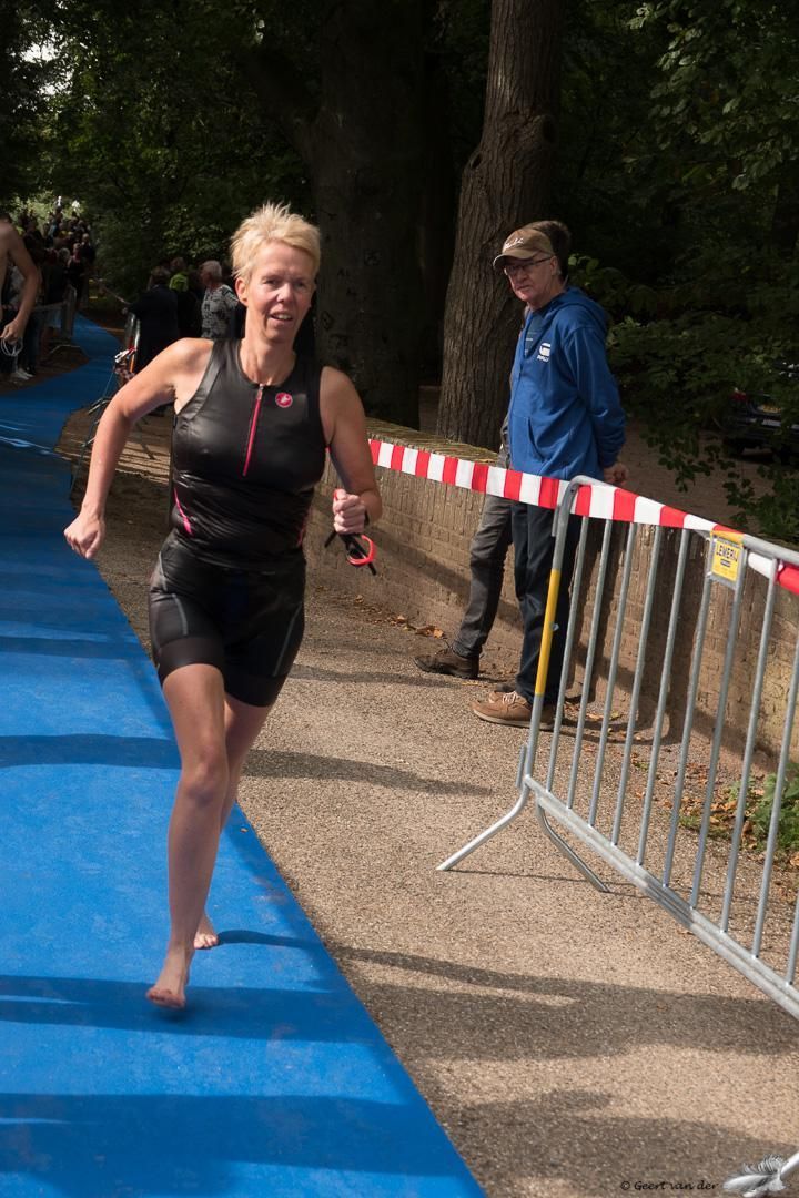 Een vrouw rent op een blauwe mat tijdens een triatlon.