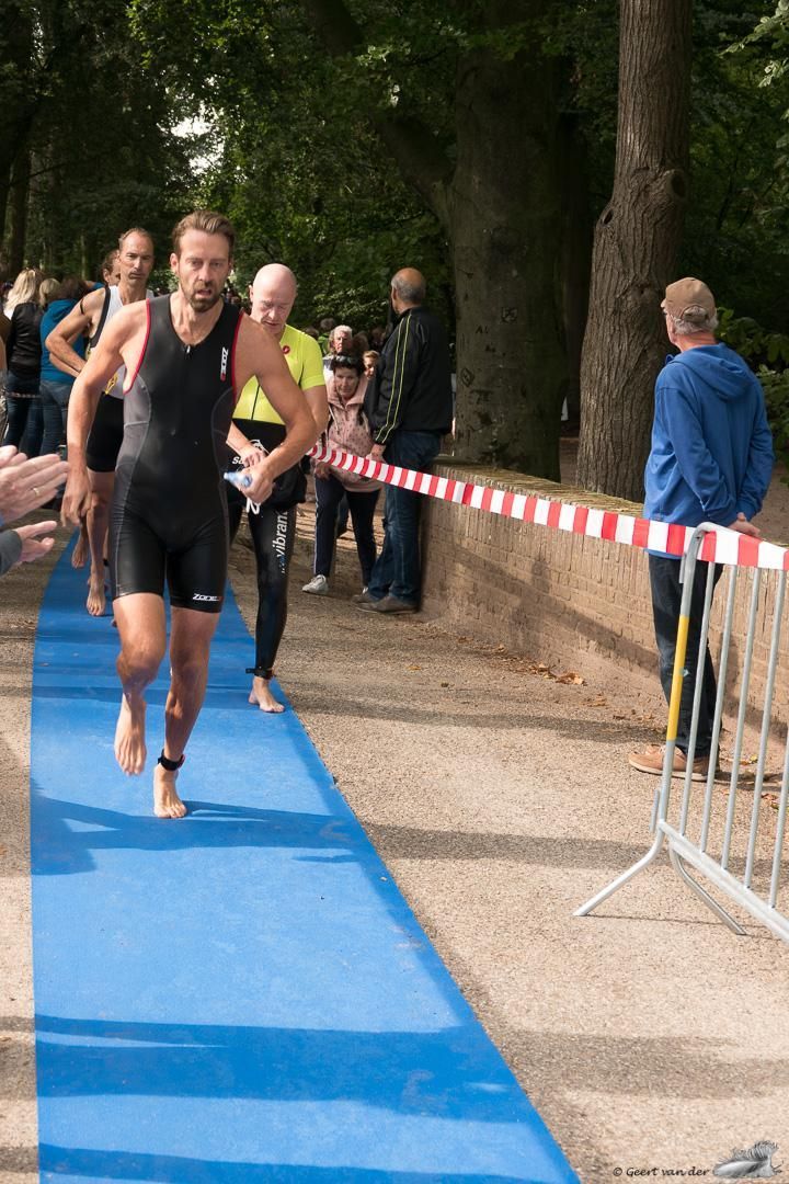 Een man in een wetsuit rent over een blauwe loper.