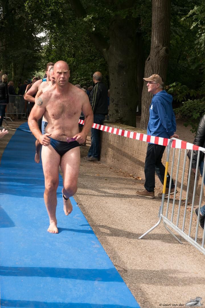 Een man zonder shirt rent op een blauwe mat.