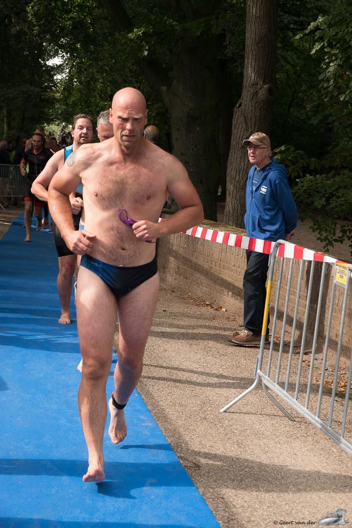 Een man zonder shirt rent op een blauwe baan.