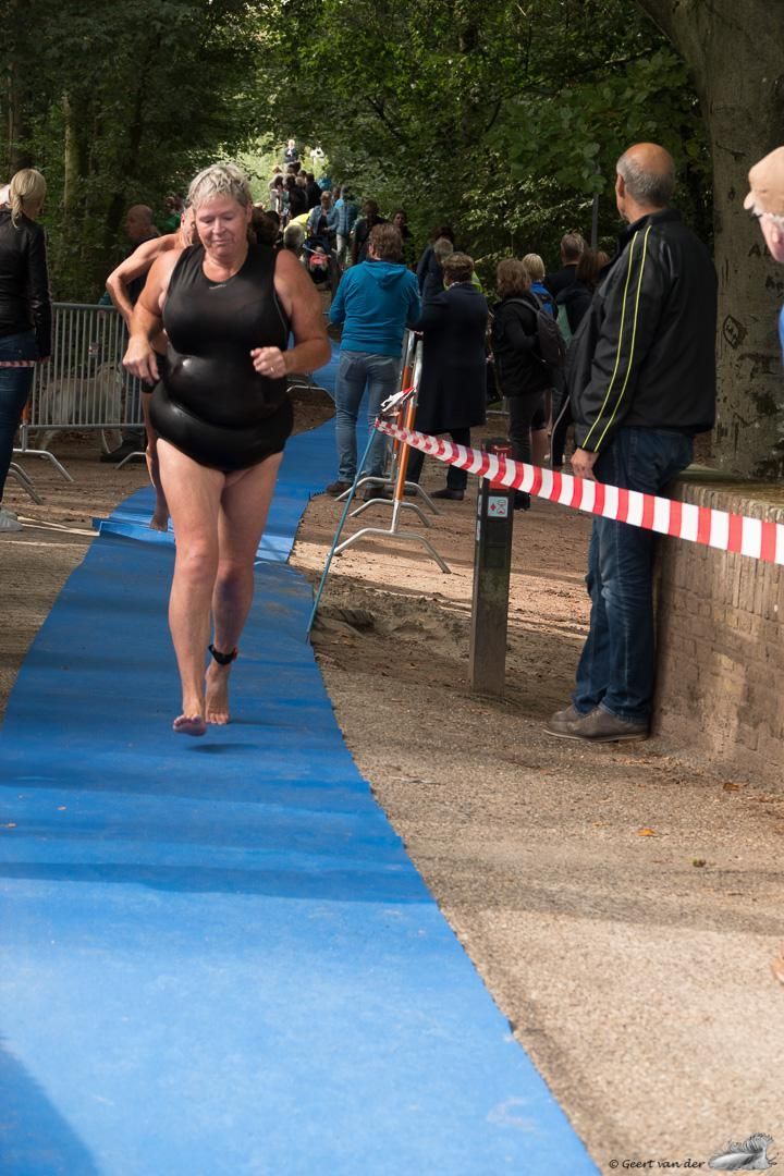 Een vrouw in een wetsuit rent op een blauwe loper.