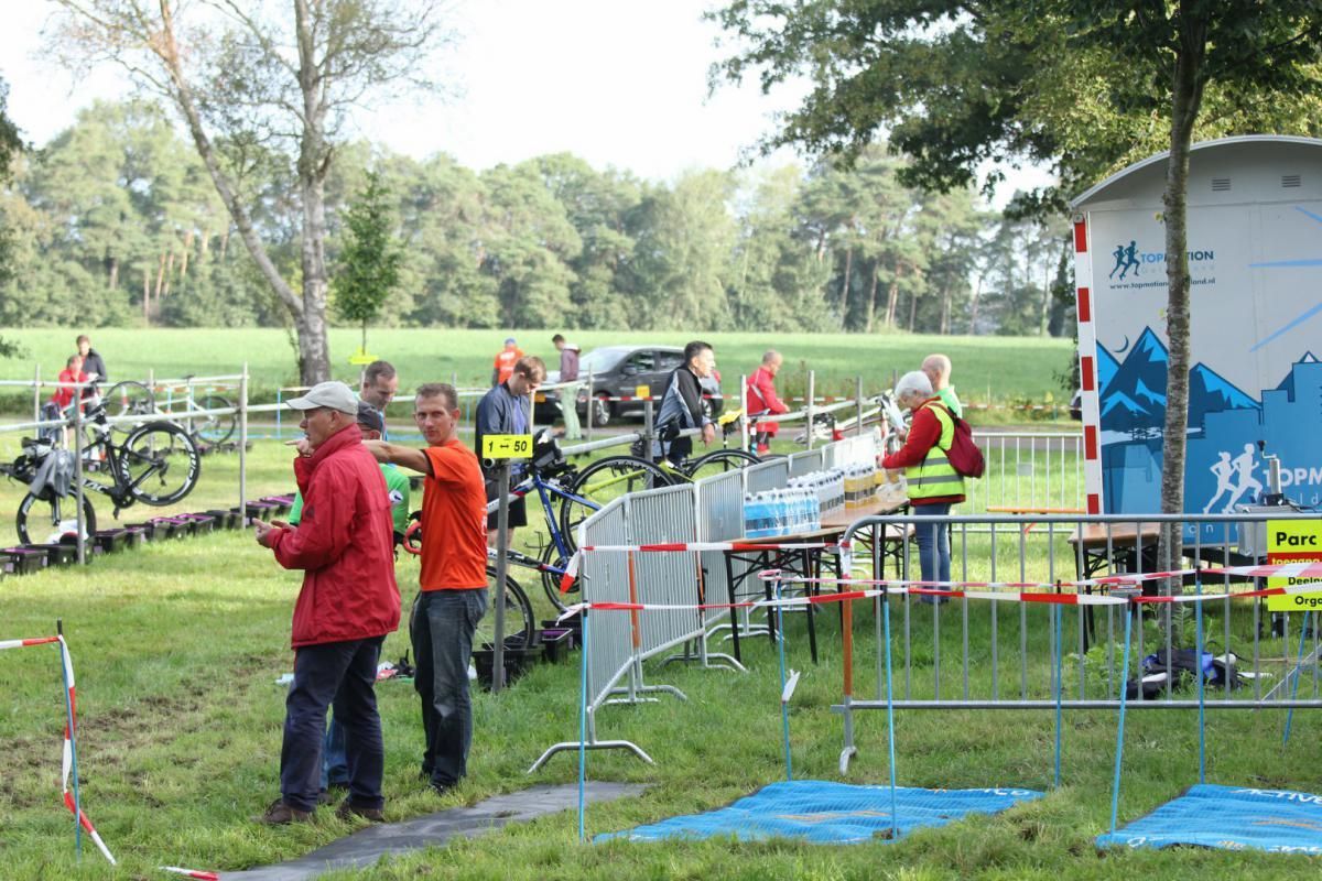Een groep mensen staat in een grasveld achter een hek.