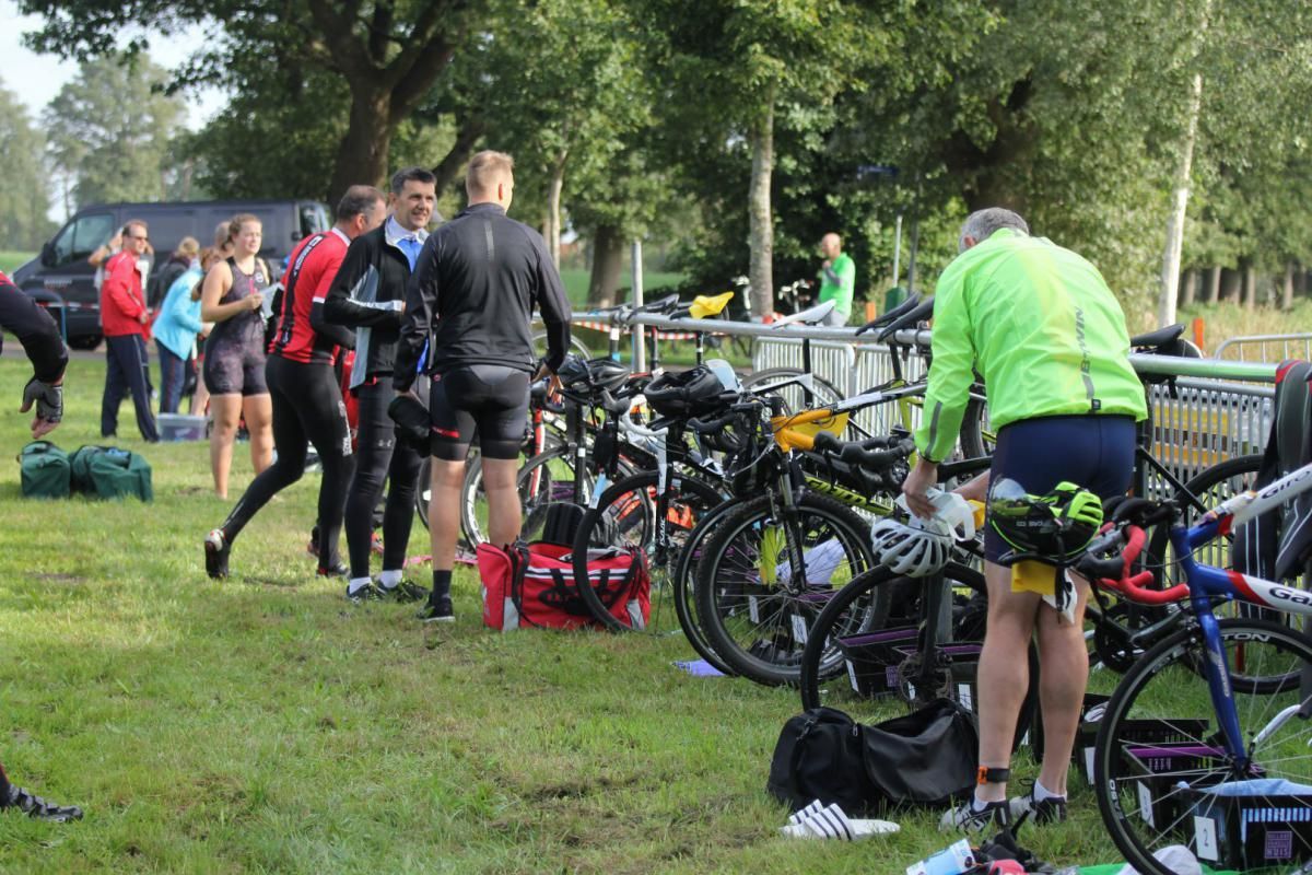Een groep mensen staat rond fietsen in een veld.