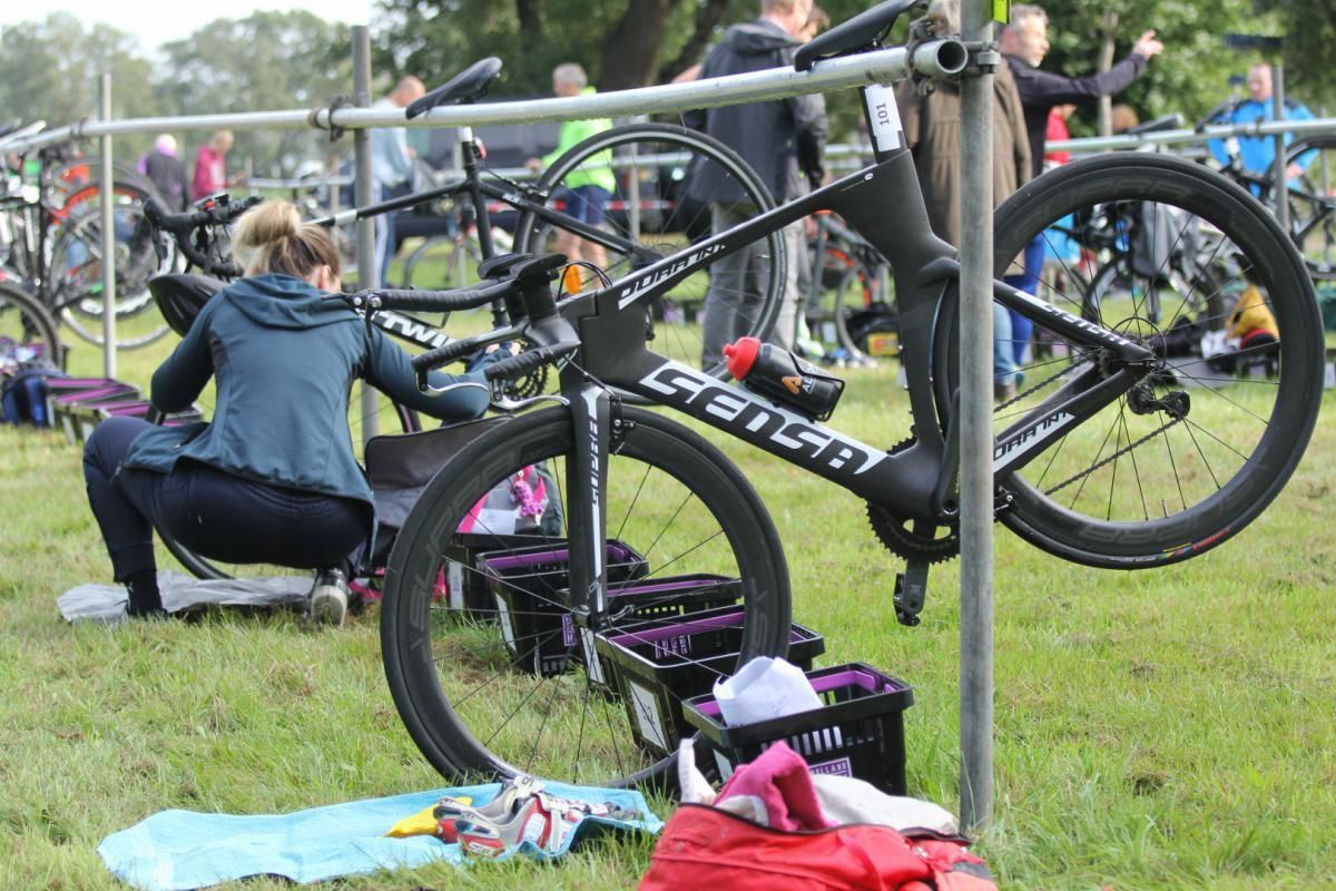 Een vrouw werkt op een fiets in een veld.