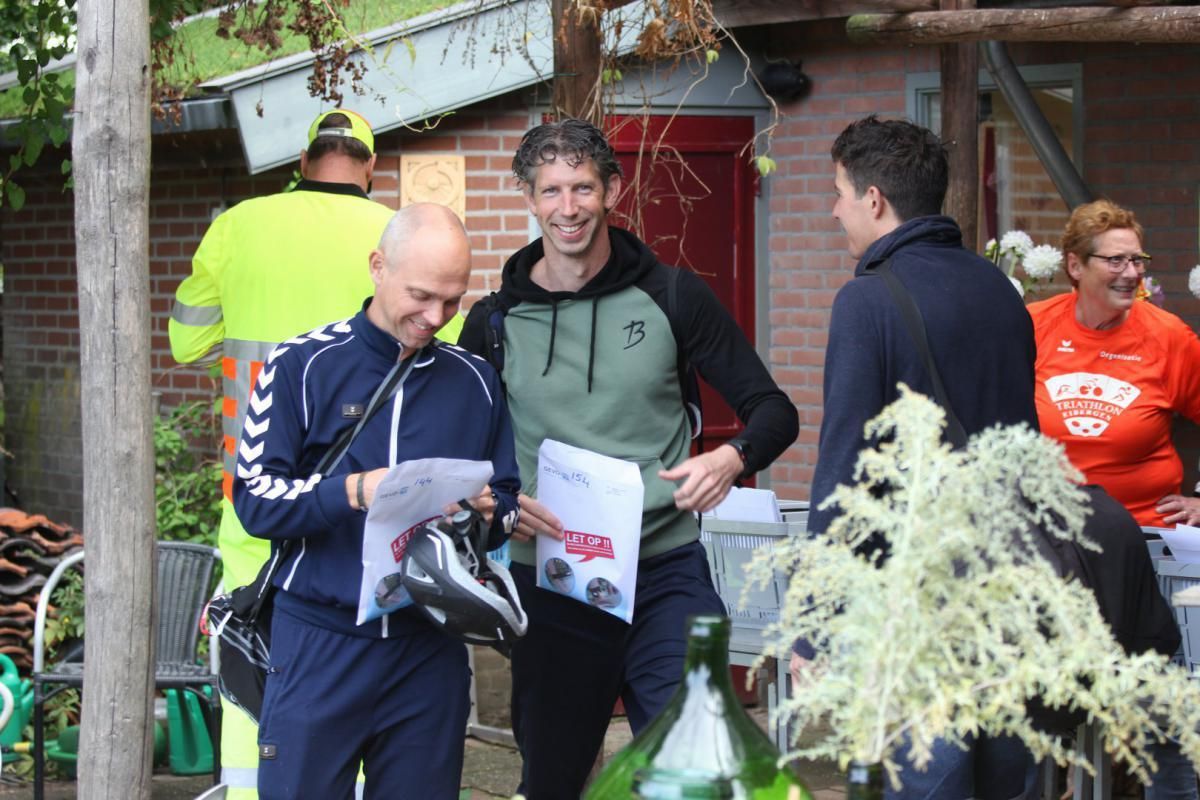 Een groep mensen staat voor een bakstenen gebouw.