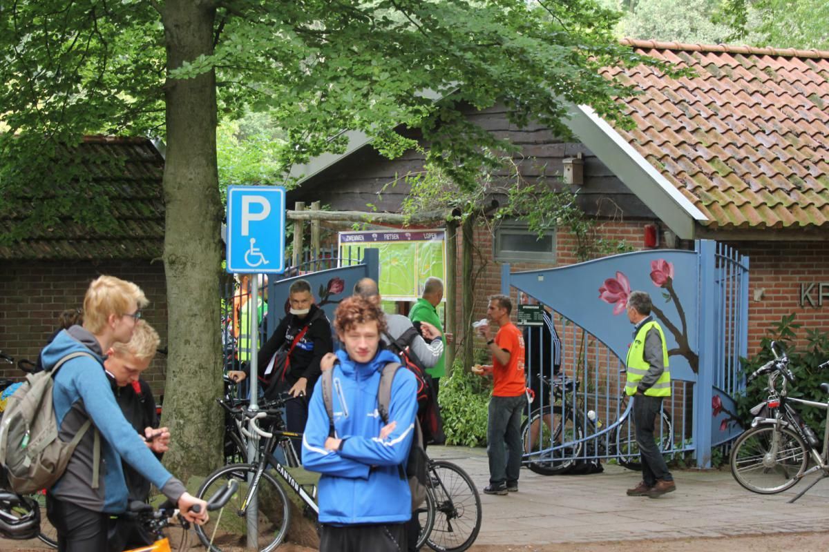 Een groep mensen staat voor een bord met een gehandicaptenparkeerplaats