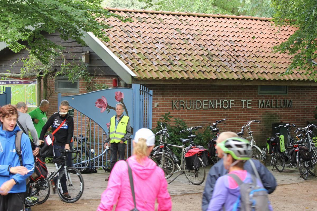 Een groep mensen staat voor een gebouw met fietsen ervoor geparkeerd.