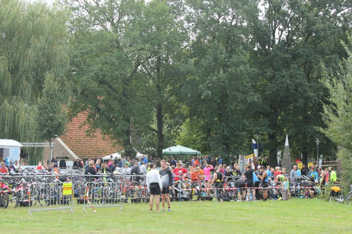 Een grote groep mensen staat in een grasveld.