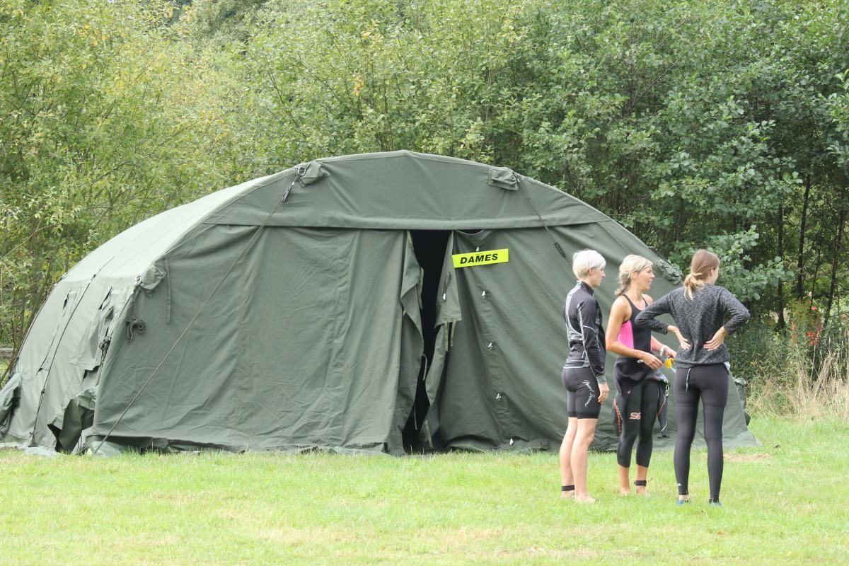 Een groep mensen staat voor een grote tent.