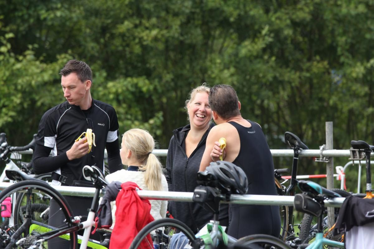 Een groep mensen staat naast fietsen en eet bananen.