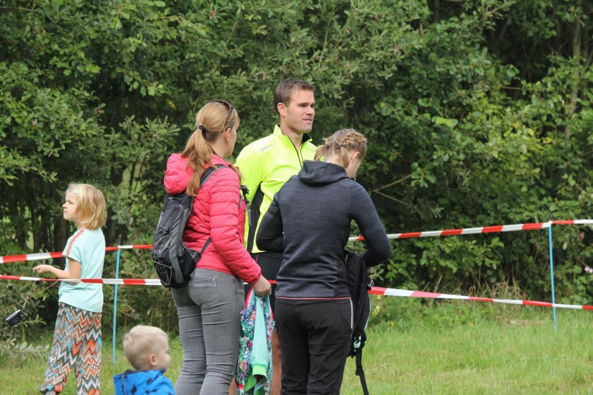 Een groep mensen staat in een veld met elkaar te praten.